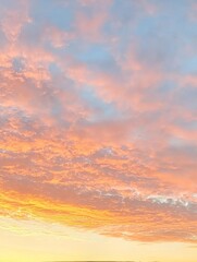 Fototapeta premium A beautiful sunset sky filled with soft pinks, oranges, and blues, showcasing fluffy clouds against a serene backdrop.