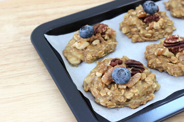 Homemade oat and banana cookie topping with blueberry, walnut and pecan on the oven tray, dessert for vegan