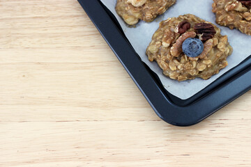 Homemade oat and banana cookie topping with blueberry, walnut and pecan on the oven tray, dessert for vegan