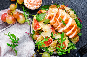 Gourmet lunch with figs, chicken, cheese, grape and herbs. Black background, top view
