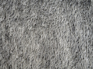 A detailed closeup showcases a dark grey shaggy wool texture. Background concept of fur texture top view. Artificial wool background