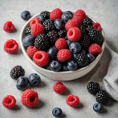 A bowl of colorful fresh berries (blueberries, raspberries, blackberries) on a plain white dish.