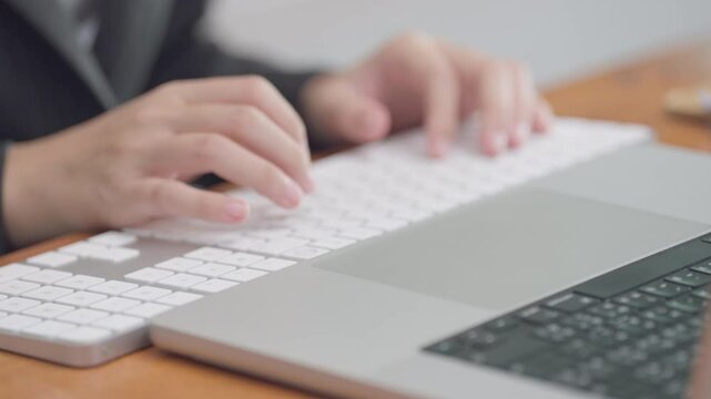 A woman is typing on a keyboard with her hand on the space bar. Concept of focus and concentration as the woman works on her computer. The black and white color scheme adds a sense of timelessness
