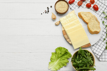 Plate with slices of delicious processed cheese, bread and fresh vegetables on white wooden table