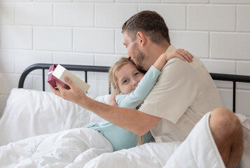 Fototapeta premium Father and daughter enjoy a joyful morning together as she surprises him with a gift in their cozy bedroom