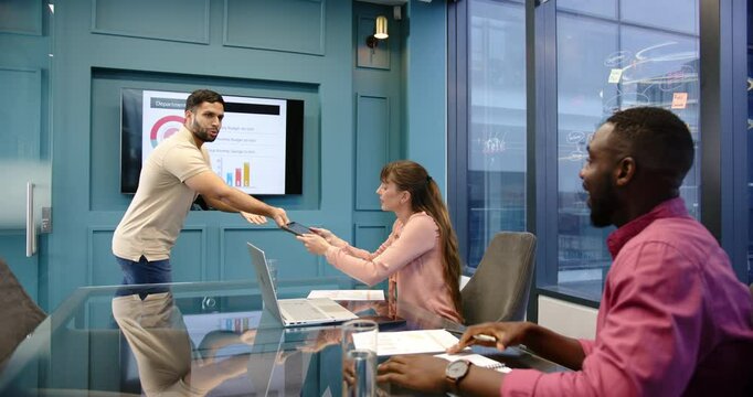 Presenting department reports, man pointing at screen while diverse colleagues discuss in office mee