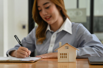 A home building representative signing documents beside a house model, symbolizing expertise and personalized service in home construction or purchase