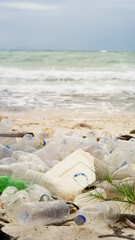Obraz premium Sandy white beach littered with plastic water bottles and polystyrene foam, concept of marine pollution