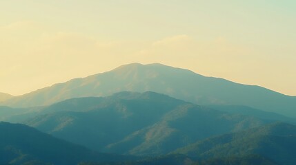 A breathtaking mountain range illuminated by the vibrant orange and yellow hues of the morning sky, with the first light of dawn creeping over the peaks