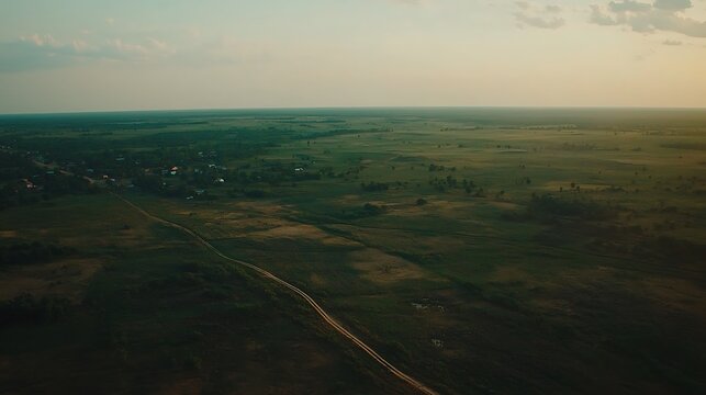 A peaceful morning sky bathed in soft golden light, gently illuminating a serene countryside with rolling hills and green fields, dotted with trees and a quiet dirt path