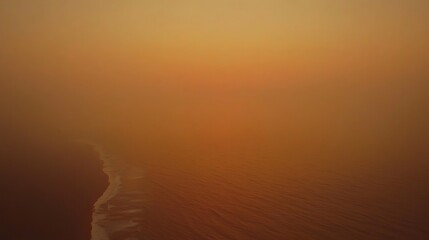 A glowing orange sky at sunset with warm hues of red, casting a beautiful reflection on the peaceful ocean