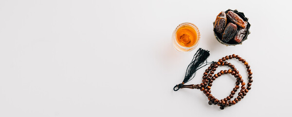 Ramadan flat lay, dates fruit, rosary beads, and tea on a clean white background. Celebrating the Muslim festival with traditional Arab elements