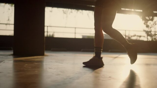 A person is running on a concrete floor with their legs apart. The image has a mood of determination and focus