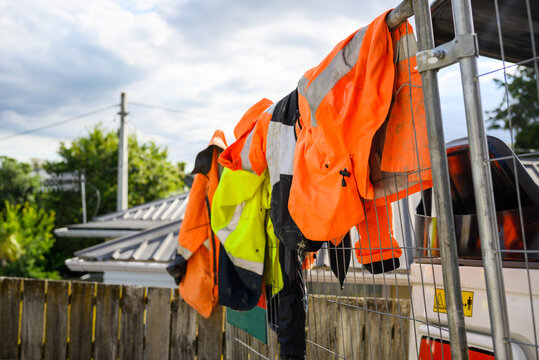 Hi-Vis work clothes hanging on protection metal fence. Construction workers taking a break.