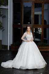 Bride at night against the backdrop of a large building with windows