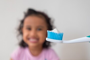 Toothbrush and a smiling little girl showing teeth in the background