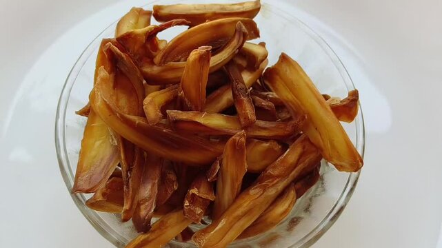 Crispy jackfruit or chakka chips deep oil fried kerala south indian snack inside bowl isolated on white table background. Closeup macro top view. Delicious unhealthy junk food.