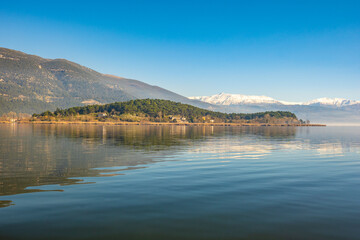 View of the Ioannina island or nissaki surrounded by the calm waters of the lake in a sunny day.
