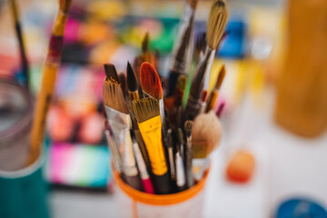 A collection of various paint brushes is placed neatly in a cup, which sits atop a table,...