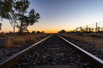 Train tracks disappearing into the distant sunrise