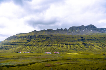 Fototapeta premium Near Reydarfjordur, eastern Iceland, a stunning view of high mountains blends seamlessly with a backdrop of dramatic, swirling clouds
