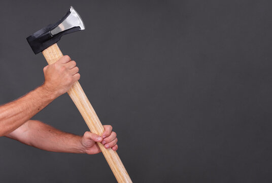 A man's hand holding an axe for chopping wood.