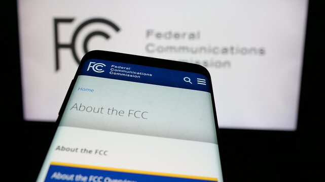 Stuttgart, Germany - 01-23-2025: Mobile phone with website of US agency Federal Communications Commission (FCC) on screen in front of logo. Focus on top-left of phone display.