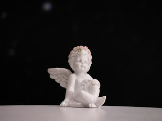 A white angel statue with a flower crown on its head is sitting on a table