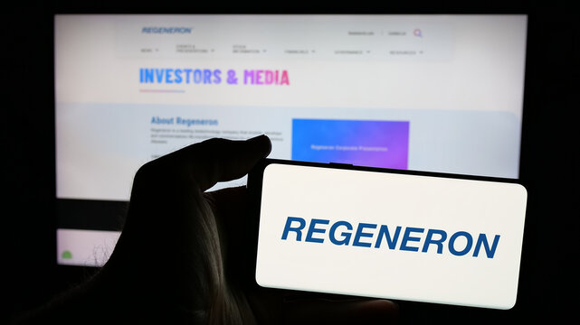Stuttgart, Germany - 01-23-2025: Person holding mobile phone with logo of US biotech company Regeneron Pharmaceuticals Inc. on screen in front of web page. Focus on phone display.