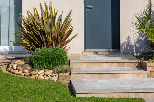 Petit jardin paysag&eacute; et ses plantes fleuries au pied d'une maison moderne.