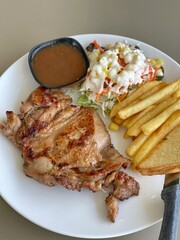 chicken steak and gravy with sausage, salad, French fries on white dish.