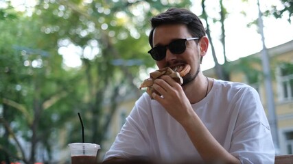 young European man eating sweet pastries on the summer terrace of a cafe on a hot summer day