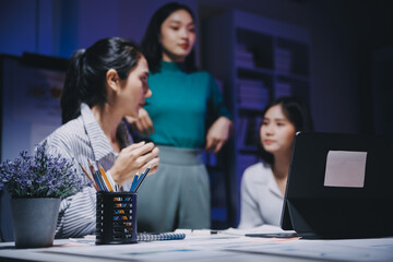 Business people working late at laptop in highrise office