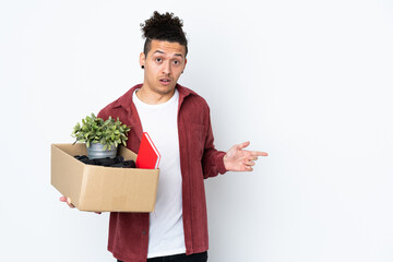 Caucasian man making a move while picking up a box full of things over isolated white background...