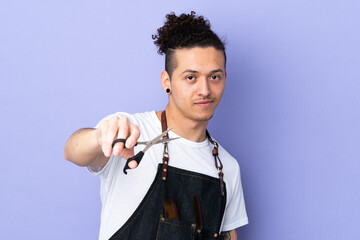 Barber man in an apron over isolated purple background