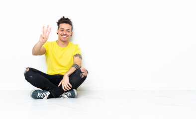 Fototapeta premium Caucasian man sitting on the floor happy and counting three with fingers
