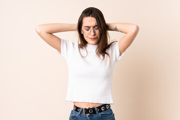 Young woman over isolated beige background frustrated and covering ears