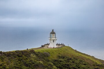 Tourists admire the Cape Reinga Lighthouse in foggy weather. Coastal scenery. CAPE REINGA, NORTHLAND, NZ