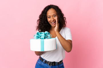 Pastry chef holding a big cake isolated on pink background shouting with mouth wide open