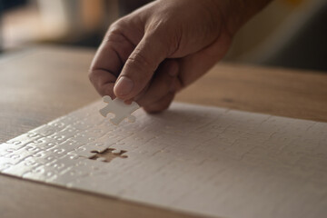 A man's hand is putting together a jigsaw puzzle.