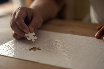 A man's hand is putting together a jigsaw puzzle.