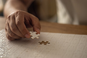 A man's hand is putting together a jigsaw puzzle.