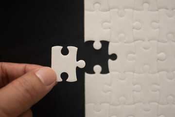 A man's hand is putting together a jigsaw puzzle.