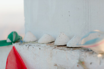 Small, white, conical objects arranged on a weathered white surface.  A red and green fabric is partially visible in the foreground.