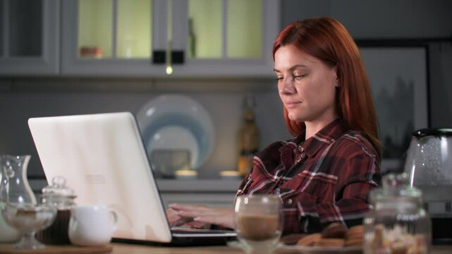 lunch snack, young woman working on laptop computer while snacking on cookies and coffee sitting at kitchen table