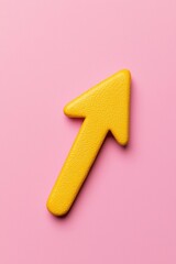Obraz premium A vibrant yellow arrow symbol on a soft pink background, representing direction, growth, and positivity in design and marketing.