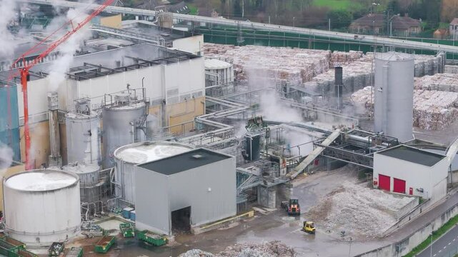 industrial plant factory during daylight oudegem belgium recycling paper operations steam rising from industry aerial drone panning shot vpk packaging group view 