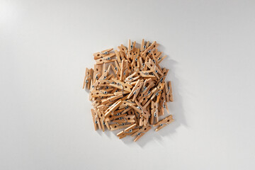 A close-up against a white background of a group of old-fashioned, unsorted wooden clips.