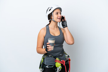 Young Ukrainian rock climber woman isolated on white background holding coffee to take away and a mobile