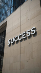 Message spelling SUCCESS on a modern building in an urban setting